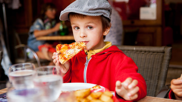 A cute little boy eating pizza